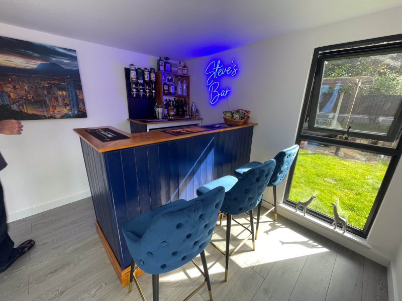 Bar area in corner of garden room with bright blue Steve's Bar sign
