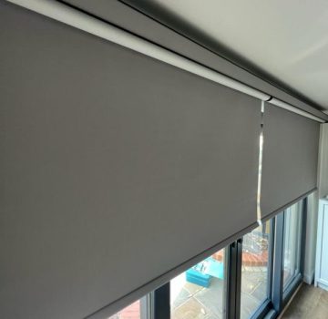 Grey roller blinds half shut on large bifold doors