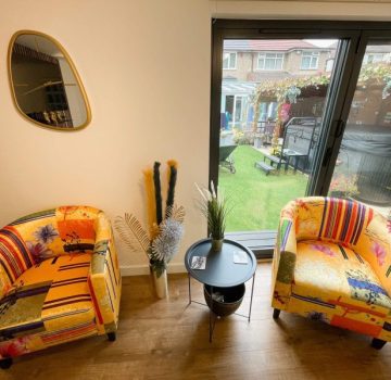 Inside garden room with two bright yellow chairs and coffee table